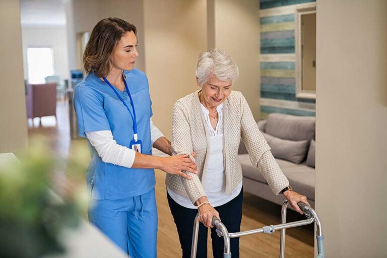 Older adults chatting and laughing together in a comfortable common area with natural light and home-like furnishings.